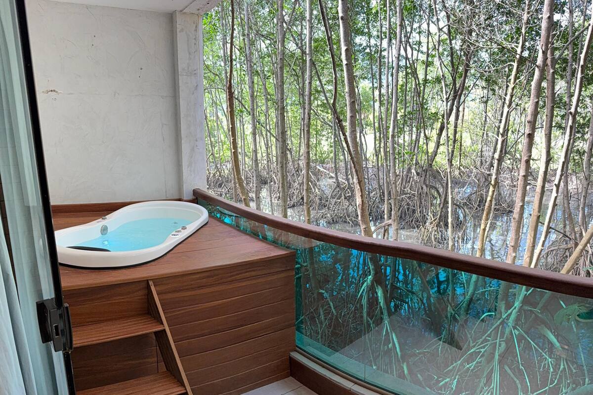 A balcony with a wooden bench and a hot tub.