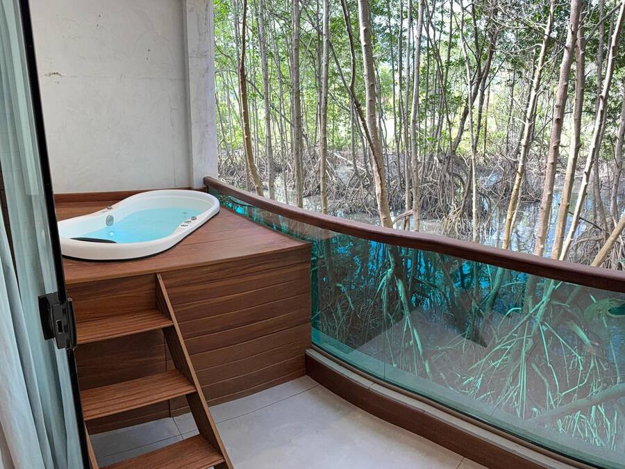 Un balcón con banca de madera y un jacuzzi.