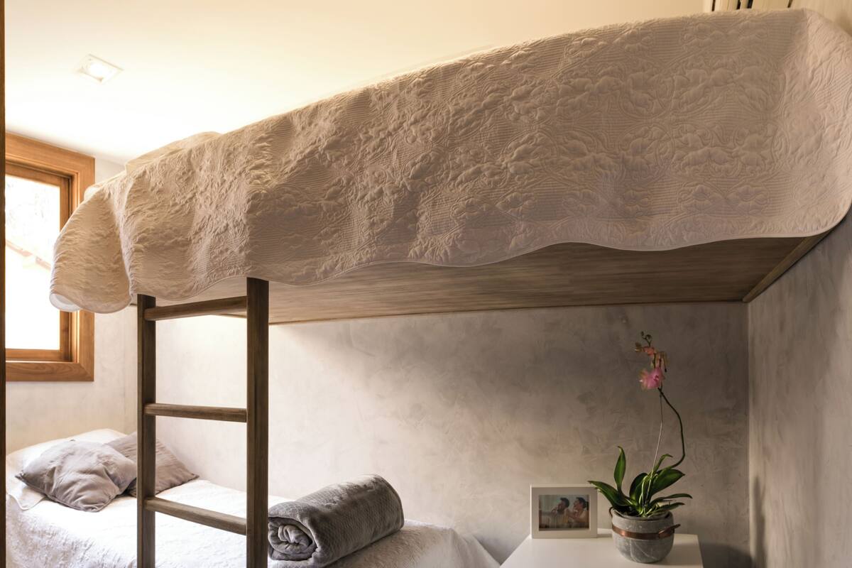 A bunk bed with a ladder, a bedside table with a plant, and a framed photo.