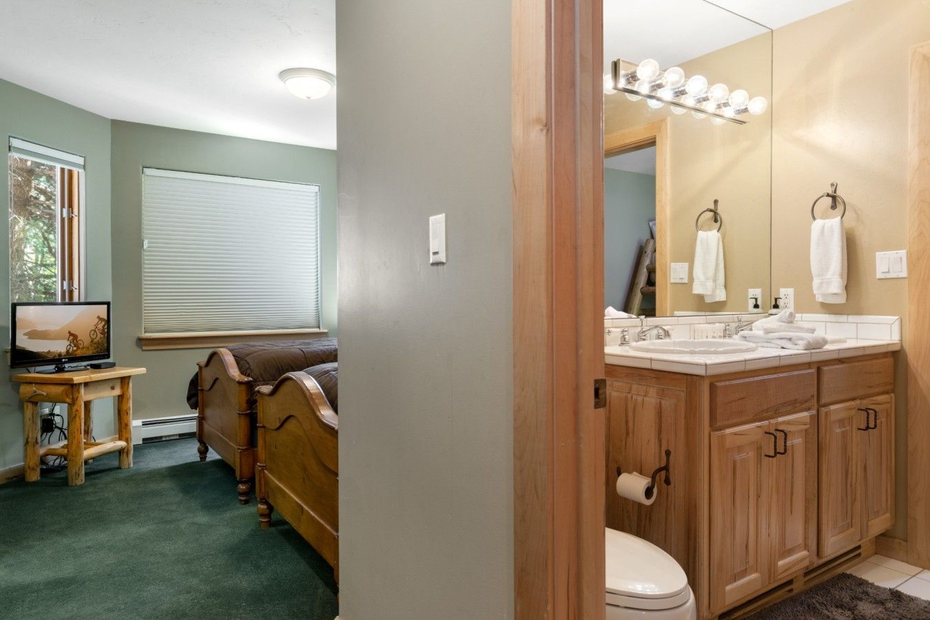 A bathroom with wooden cabinets, a toilet, a sink with a mirror, and a vanity with a towel ring.