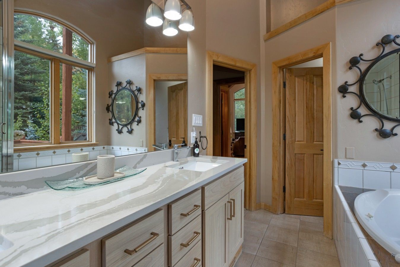 A bathroom with a large vanity, a bathtub, and a mirror with decorative frames.