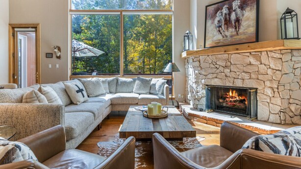 Una sala de estar acogedora con chimenea de piedra, ventanas amplias y un espacio de estar confortable.