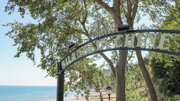 Ein Strand mit einem Schild, auf dem 'SHANKENBACHITE' steht, und Blick aufs Meer.