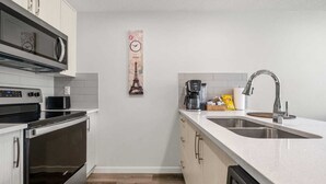 Una cocina compacta con microondas, horno, cafetera y pileta.