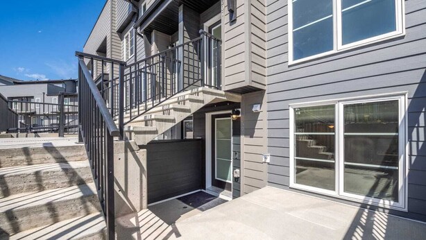 Un edificio residencial de varios pisos con una escalera que conduce a la entrada, una puerta de garaje y ventanas amplias.