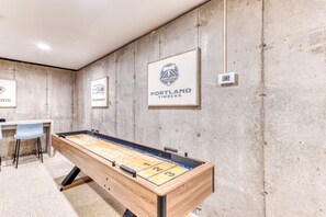 Una habitación con mesa de fútbol, zona de bar y pared con logotipos enmarcados.