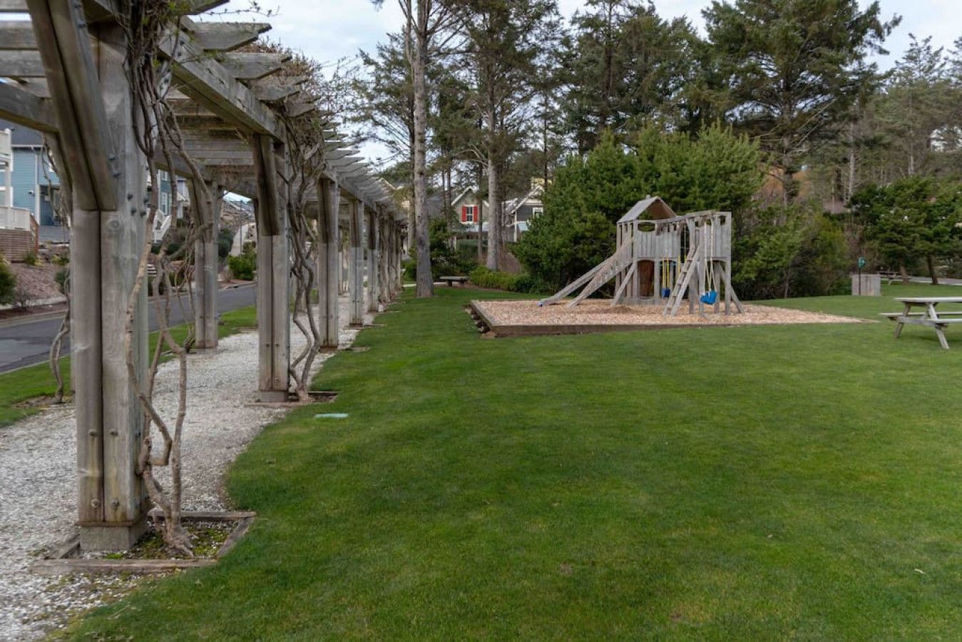 Ein Park mit einem Spielplatz, einem Picknicktisch und einem überdachten Weg.