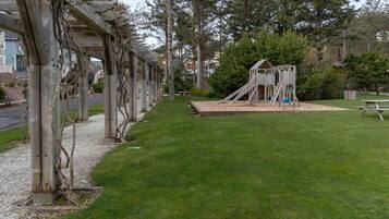 Ein Park mit einem Spielplatz, einem Picknicktisch und einem überdachten Weg.