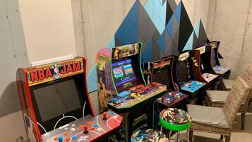 Ein Raum mit Spielautomaten, darunter NBA JAM und Mortal Kombat, sowie ein Korbstuhl.