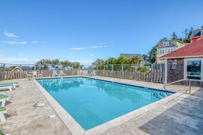 Una piscina rectangular con cubierta de madera y sillas de descanso.