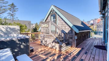 Eine Holzterrasse mit integriertem Whirlpool, einer Treppe und Blick auf die umliegende Wohngegend.