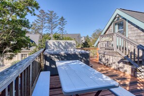 Una terraza de madera con una mesa de picnic y un jacuzzi.