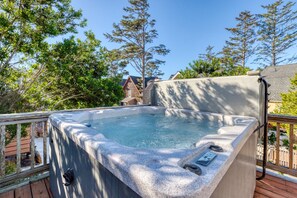 Un jacuzzi en una terraza de madera con vistas despejadas a árboles circundantes y un edificio distante.