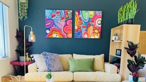 A modern living room with a sofa, coffee table, and artwork on the wall. - Larger Room In Parap, saltwater pool, close to markets, Great coffee, Central. (Parap)