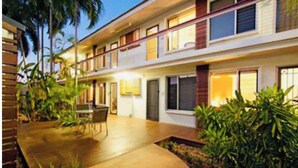 A multi-story hotel with a flat roof, outdoor seating area, and lush greenery. - Larger Room In Parap, saltwater pool, close to markets, Great coffee, Central. (Parap)