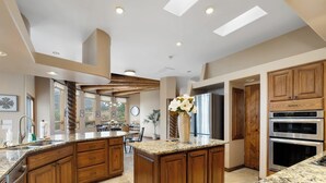 A spacious kitchen with granite countertops, wooden cabinets, and stainless steel appliances.