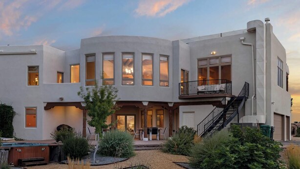 A modern two-story house with a covered patio, a pool, and a well-maintained garden.