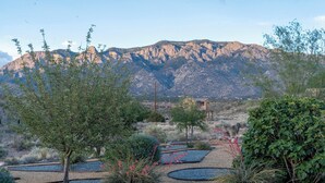 A desert landscape with a house, gravel pathways, and sparse vegetation.