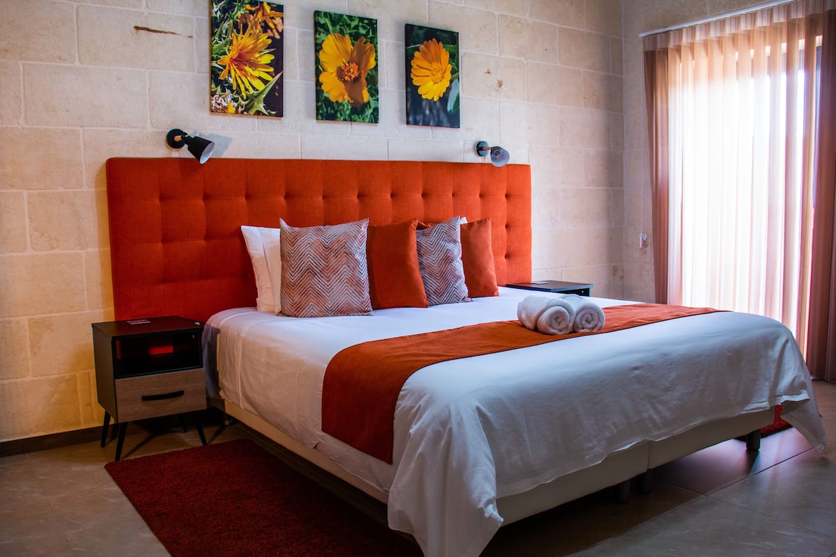 Ein Hotelzimmer mit einem großen Bett, einem roten Kopfteil und drei Blumenbildern an der Wand.