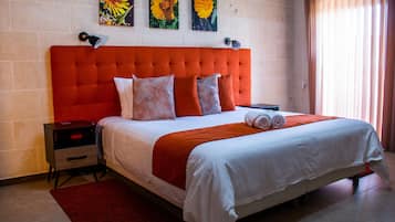 A hotel room with a large bed, a red headboard, and three flower paintings on the wall.