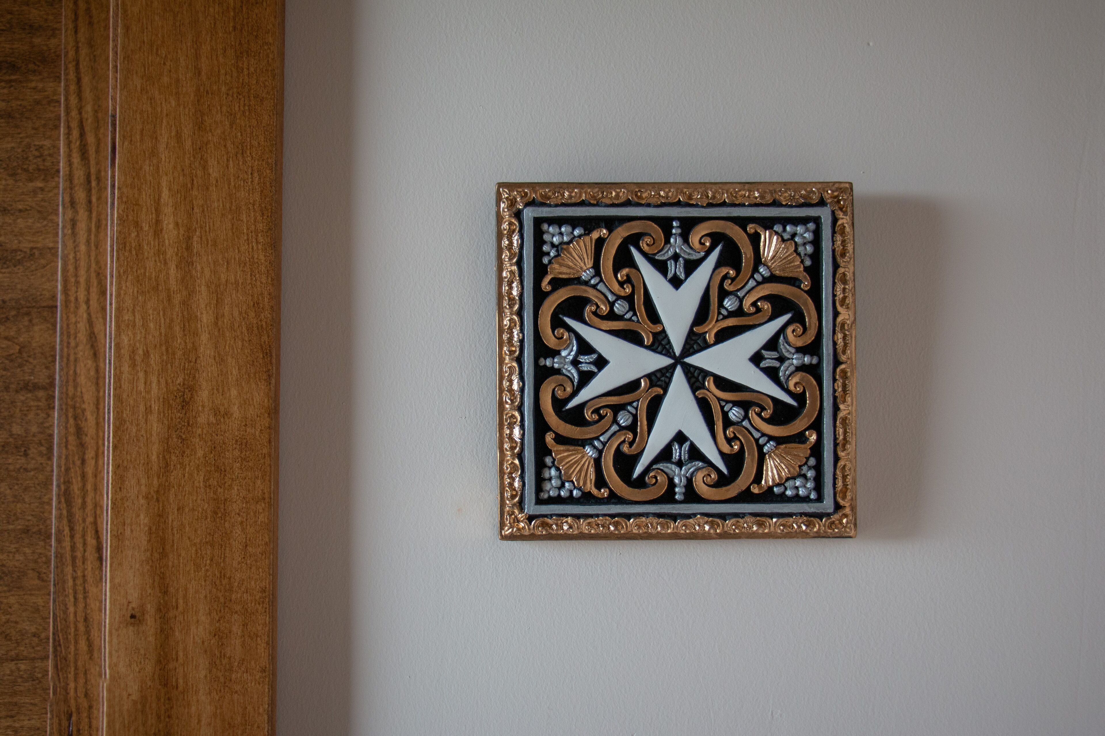 Una pieza decorativa de pared con diseño geométrico, enmarcada en dorado.