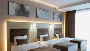 A hotel room with two beds, a wooden floor, and artwork on the walls. - Modern Hotel (Tashkent)