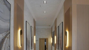 A hallway with marble flooring, framed artwork on the walls, and recessed lighting. - Modern Hotel (Tashkent)