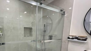 A modern bathroom with a glass-enclosed shower, a white bathtub, and a white sink. - Modern Basement Studio w/ Kitchen, Free Parking (Montréal)