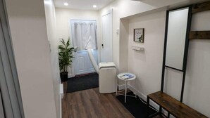 A compact room with a shower, a small table, a bench, and a potted plant. - Modern Basement Studio w/ Kitchen, Free Parking (Montréal)