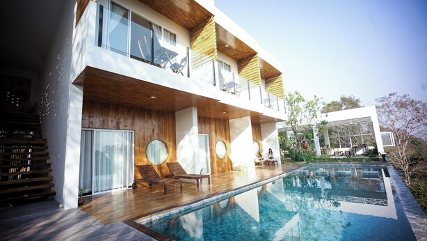 A modern two-story building with a swimming pool, wooden deck, and outdoor seating area. - HOMU Villa Pua (Pua)