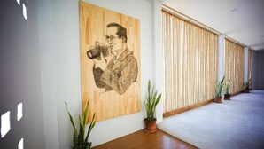 A hallway with a wooden floor, potted plants, and a large wall art depicting a person with a camera. - HOMU Villa Pua (Pua)