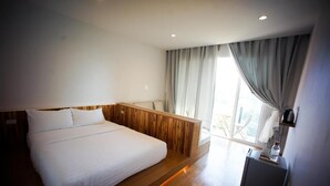 A modern hotel room with a large bed, wooden headboard, and a view of the outdoors. - HOMU Villa Pua (Pua)