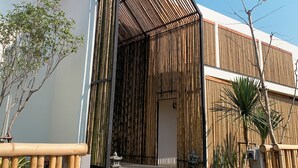 A modern building with a bamboo facade, a clear sky, and a stone pathway leading to the entrance. - HOMU Villa Pua (Pua)