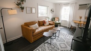 A modern living room with a leather sofa, a dining table, and a TV. - Yellowbird Retreat of Walla Walla Valley (College Place)