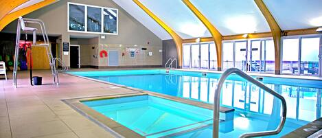 En indendørs swimmingpool med tydelige baner, en redningsbadsstol og en stige.