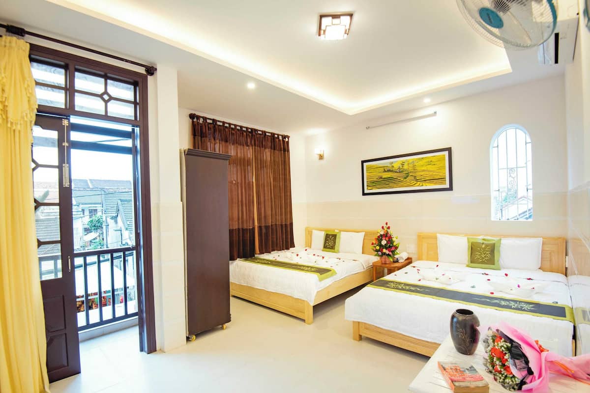A hotel room with two beds, a large window, a balcony, and a ceiling fan.
