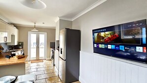 Une cuisine moderne dotée d’un grand téléviseur à écran plat fixé au mur, qui affiche l’interface d’un service de diffusion en continu.