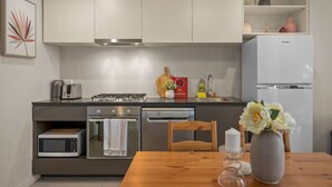 Una cocina compacta equipada con estufa a gas, microondas, horno y refrigerador.