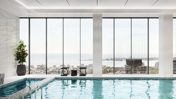 Una piscina interior moderna con vistas a la ciudad, amplias ventanas y un diseño minimalista.