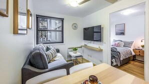 Ein modernes Zimmer mit einer Couch, einem Esstisch, einem Fernseher und einem Bett.