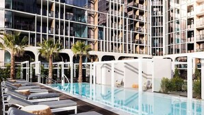 A rooftop pool area with lounge chairs and a view of a modern building with balconies. - Premium Chic: A Relaxing Retreat (Port Melbourne)
