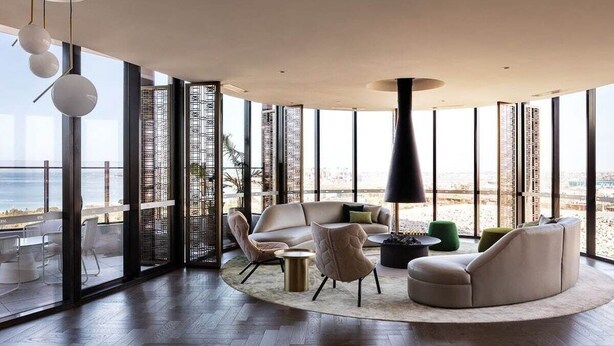 A modern living room with a large window overlooking the beach, furnished with a sofa, chairs, and a coffee table. - Premium Chic: A Relaxing Retreat (Port Melbourne)