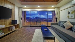Un salon moderne doté d’un grand téléviseur, d’un canapé, d’une table basse et d’un balcon offrant une vue sur la ville.