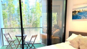 Un dormitorio con una cama grande, un balcón con sillas y un cuadro en la pared.