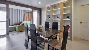 A modern dining area with a marble table and black chairs, a green sofa, and a built-in bookshelf with decorative items. - ✈Sea-view 80sqm-1 Bedroom Home-Patong Beach (Tambon Patong)