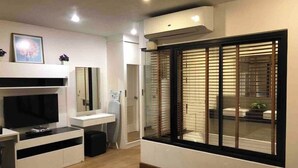 A modern living room with a flat-screen TV, a sofa, and a large window with blinds. - ✈Sea-view 80sqm-1 Bedroom Home-Patong Beach (Tambon Patong)