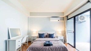 A modern bedroom with a bed, bedside tables, a desk, and a large window.