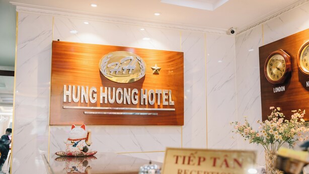 A reception desk with a sign for Hung Huong Hotel and a clock indicating London time. - HUNG HUONG HOTEL (Ho Chi Minh City)