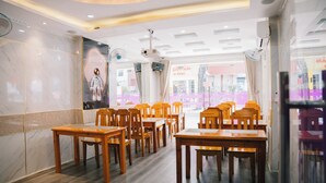 A restaurant interior with wooden tables and chairs, a ceiling with recessed lighting, and a view of the street outside. - HUNG HUONG HOTEL (Ho Chi Minh City)
