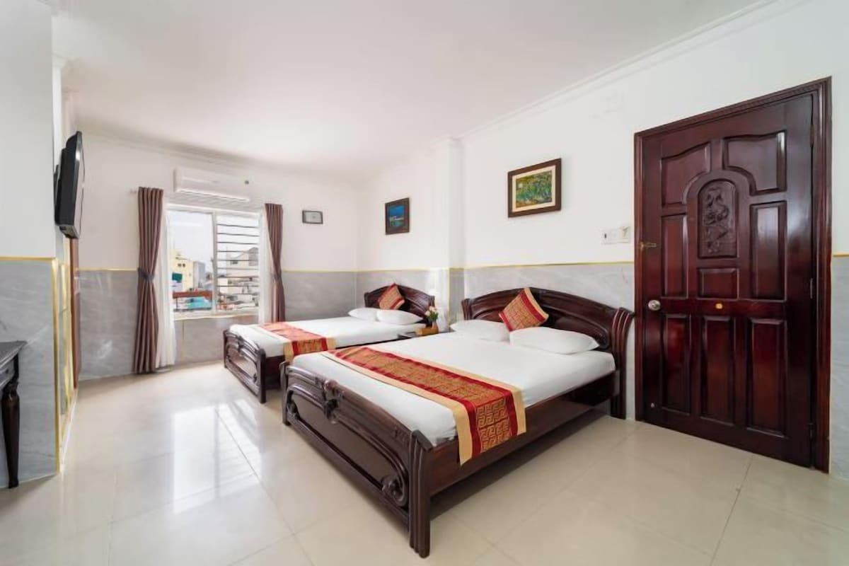 A hotel room with two beds, a TV, and a door.